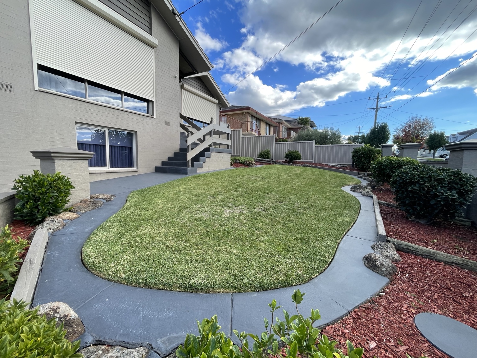 Freshly maintained lawn with curved concrete edging and tidy garden beds at a Melbourne property